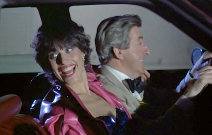 8 Lorraine Bracco laughing inside a car next to a man in a tuxedo, portraying her character Bubble in the 1979 French film Duos sur canapé.