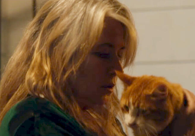 12 Lorraine Bracco looking down at her orange tabby cat in Jacir film scene.