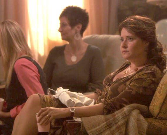 5 Lorraine Bracco sitting on a couch looking a bit sad next to family members in a scene from the movie Snowglobe.