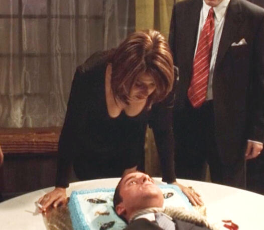 6 Lorraine Bracco leaning over a table with her son lying down on a cake in Crazy for Love.