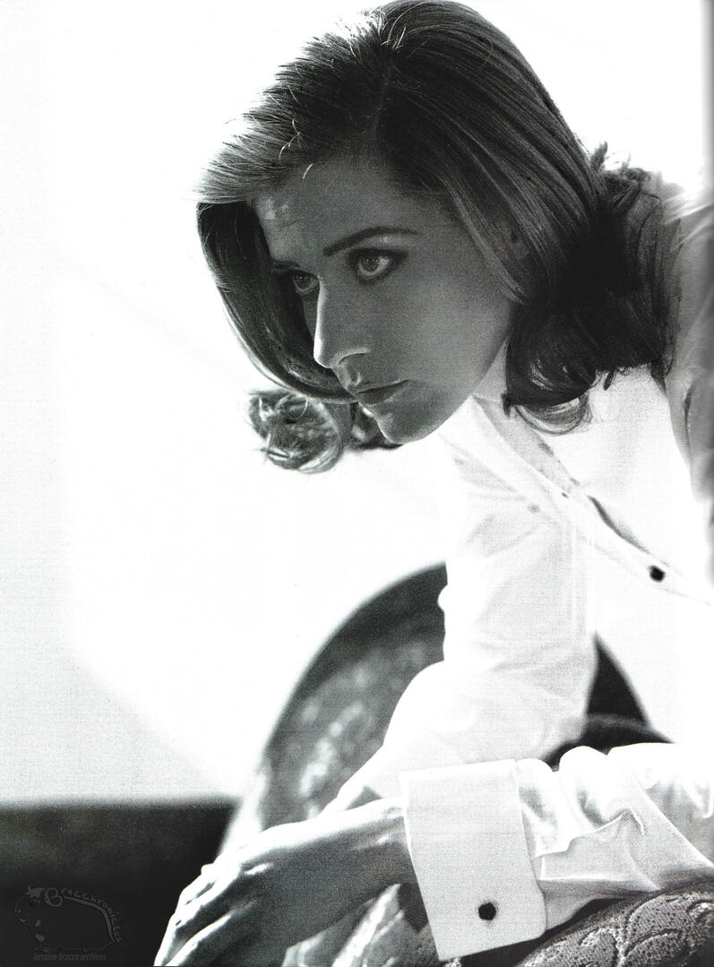Continuation of Mirabella magazine with Black and white fashion photography portrait of actress Lorraine Bracco wearing a structured white Giorgio Armani cotton dress shirt with French cuffs, leaning forward.