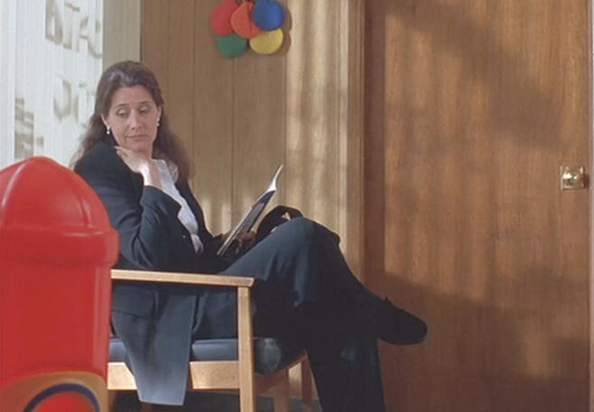 7 Lorraine Bracco sitting and reading in an waiting room in Silent Cradle.