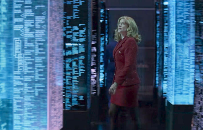 7 Lorraine Bracco walking through a corridor of digital data server screens in the movie Hackers.