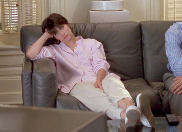 2 Lorraine Bracco lounging on a leather sofa in The Dream Team movie.