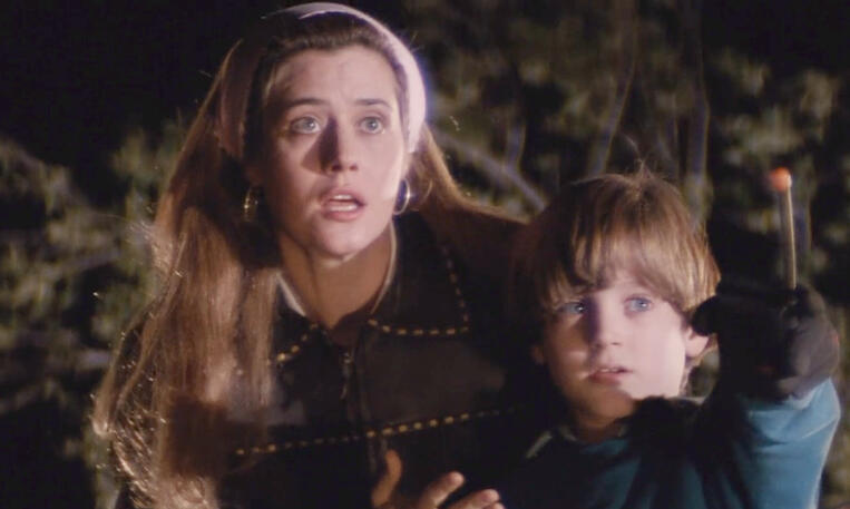 1 Lorraine Bracco looking concerned outdoors at night holding a young Elijah Wood in the movie Radio Flyer.