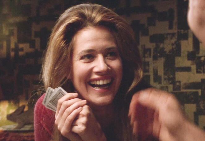 2 Lorraine Bracco laughing happily while holding playing cards in a scene from the 1992 film Radio Flyer.