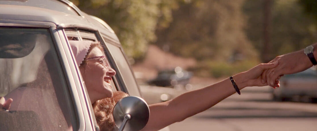 10 Lorraine Bracco leaning out of a car window smiling with her arm extended in Radio Flyer.