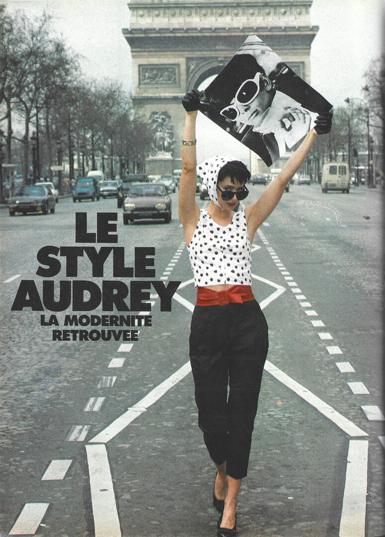 Elle magazine feature layout titled Audrey's Style. Lorraine Bracco stands in the street with the Arc de Triomphe behind her, wearing a polka dot top, black pants, a red belt, and holding a black-and-white portrait of Audrey Hepburn above her head.